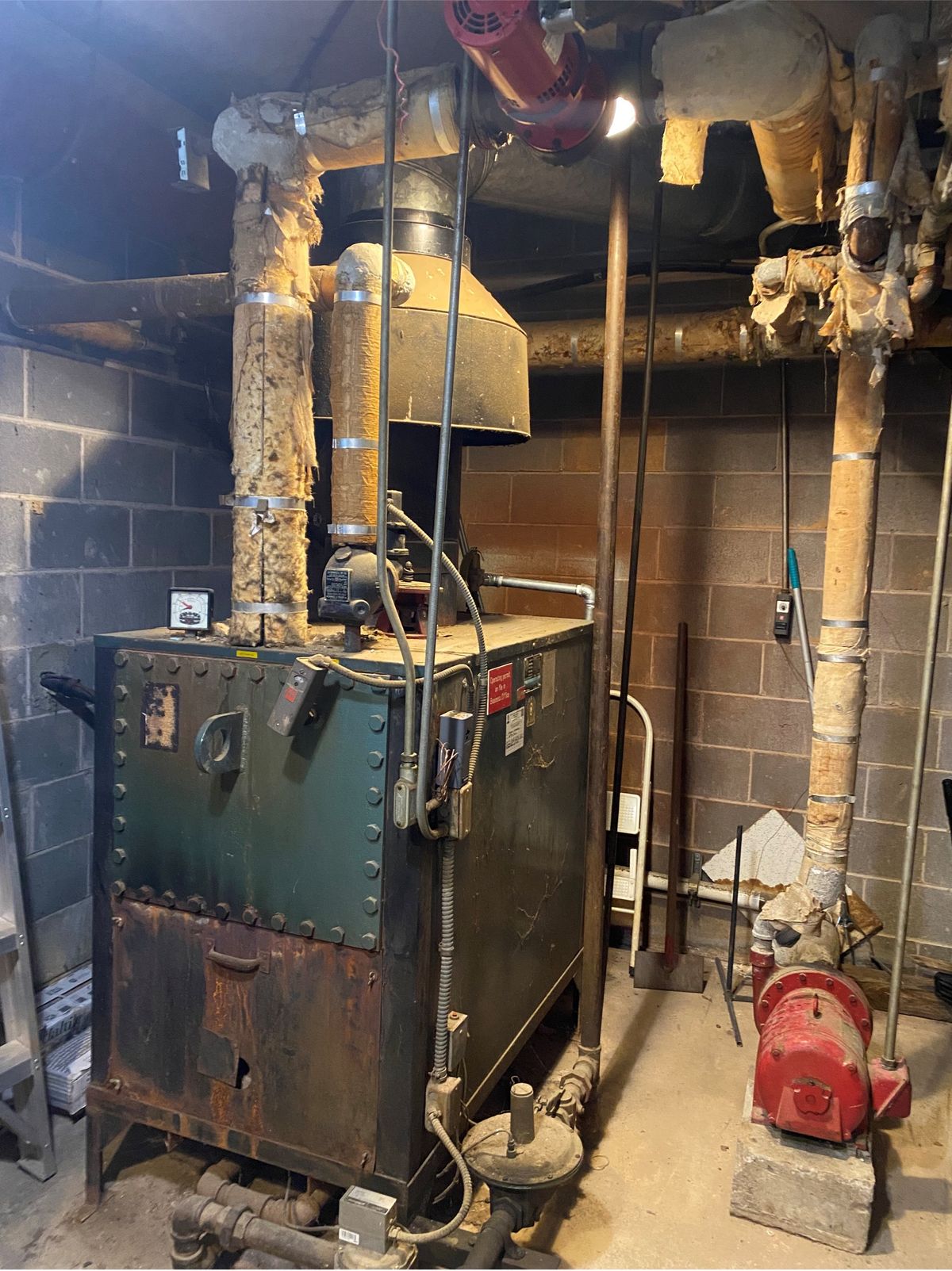 The church's 1961 boiler: a riveted, rusting unit in the education building's mechanical room, the insulation on its pipes crumbling