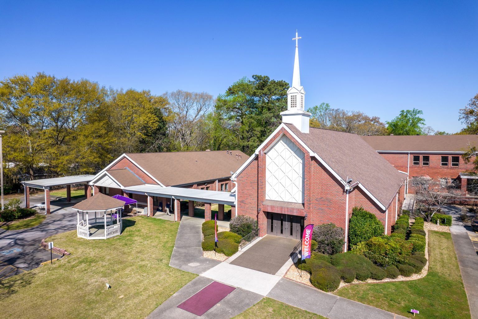 Lithia Springs Methodist Church from above: the sanctuary with its steeple and diamond-paned gable, the education building behind it, and the gazebo and covered walkways joining the campus